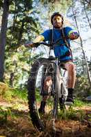 Male mountain biker with bicycle in the forest