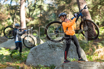 Biker couple holding their mountain bike and walking in forest