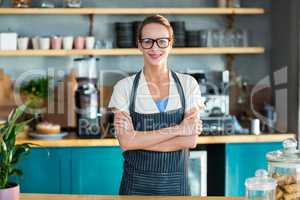 Portrait of smiling waitress standing with arms crossed