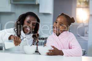 Portrait of daughter and daughter pouring milk in a bowl