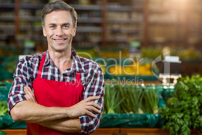 Smiling male staff standing with arms crossed in organic section