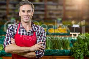 Smiling male staff standing with arms crossed in organic section