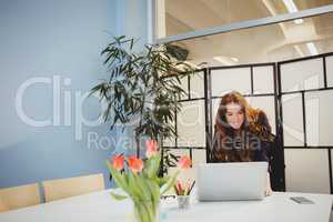 Confident executive using laptop in meeting room at creative office