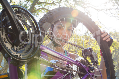 Female cyclist repairing her bicycle in park