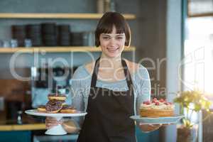 Portrait of waitress holding doughnuts and cake in cafÃ?Â©