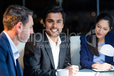 Businessman smiling at camera while colleagues looking at document