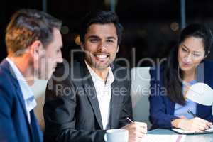 Businessman smiling at camera while colleagues looking at document