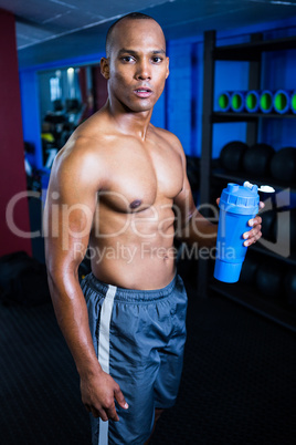 Muscular shirtless man holding bottle