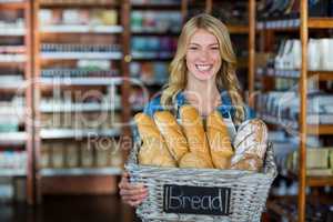 Smiling female staff holding a basket of breads