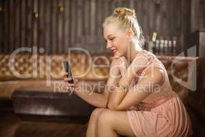 Beautiful woman sitting on sofa and using mobile phone