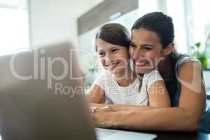 Mother and daughter using laptop and digital tablet in the living room