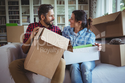 Couple talking on the sofa while unpacking cartons