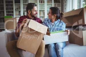 Couple talking on the sofa while unpacking cartons