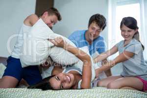 Family having pillow fight in bedroom