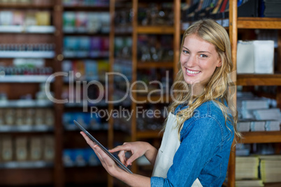 Smiling female staff using digital tablet in supermarket
