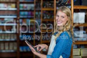 Smiling female staff using digital tablet in supermarket