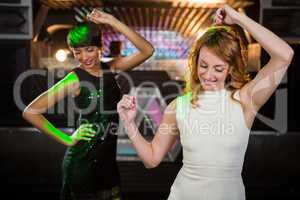 Smiling female friends dancing on dance floor