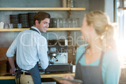 Waiter and waitress working in kitchen at cafÃ?Â©