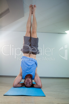 Man performing sirsasana on exercise mat