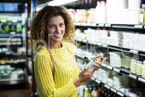 Smiling woman buying a bottle of oil in supermarket