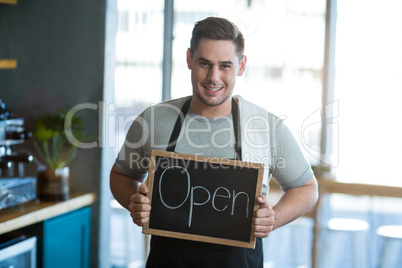 Smiling waiter showing slate with open sign