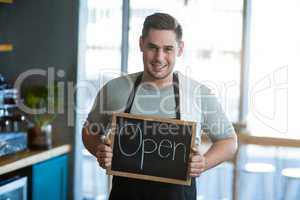 Smiling waiter showing slate with open sign