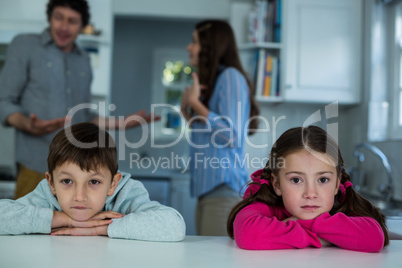 Upset children sitting while couple arguing with each other