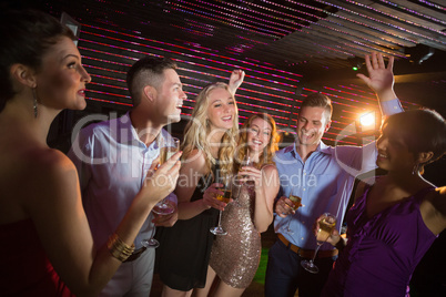 Smiling friends holding glasses of champagne while dancing