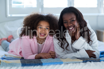 Portrait of mother and daughter lying on bed