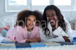 Portrait of mother and daughter lying on bed