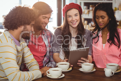 Group of friends using digital tablet while having cup of coffee