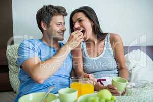 Smiling couple having breakfast on bed