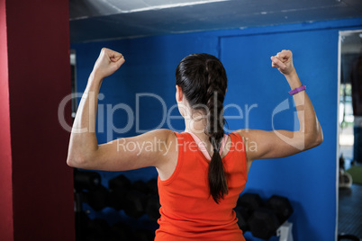 Rear view of woman flexing muscles in gym