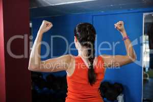 Rear view of woman flexing muscles in gym