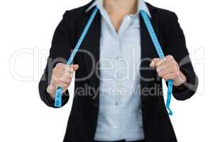 Businesswoman holding a measuring tape against white background