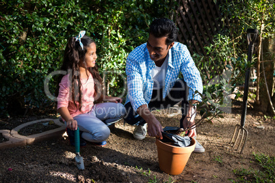 Father and daughter potting a plant in pot at backyard