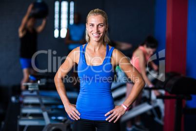 Portrait of happy fit woman with hands on hip in gym