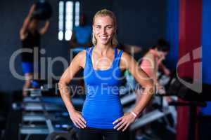 Portrait of happy fit woman with hands on hip in gym