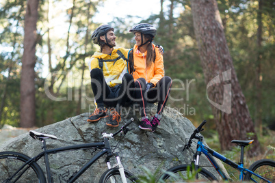 Biker couple sitting on rock and interacting with each other