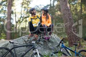 Biker couple sitting on rock and interacting with each other