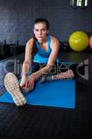 Portrait of young athlete stretching in gym