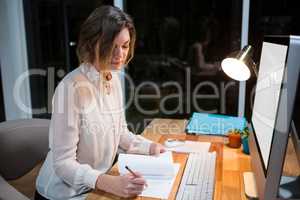 Businesswoman writing on paper at her desk