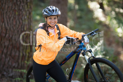 Female biker standing with mountain bike in forest