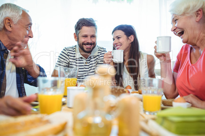 Happy couple and parents talking while having breakfast