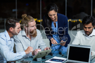 Businesswoman discussing with colleagues over digital tablet