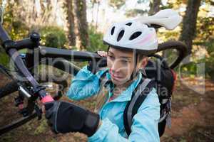 Female mountain biker carrying her bicycle in the forest