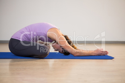 Woman doing yoga child pose on exercise mat