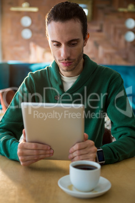 Man using digital tablet and coffee cup on table