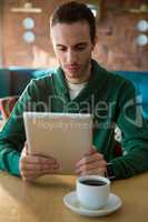 Man using digital tablet and coffee cup on table