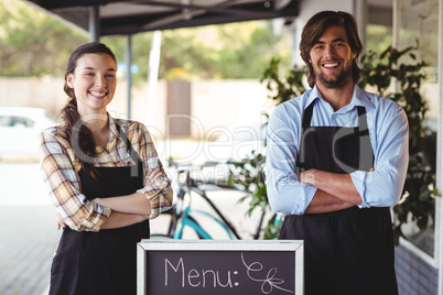 Waiter and waitress standing with menu board outside the cafe